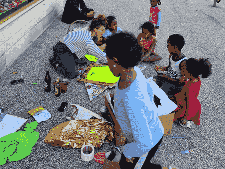 des enfants avec une artiste bricolent dans la rue