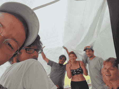 des artistes s'abritent sous une bâche pendant la pluie